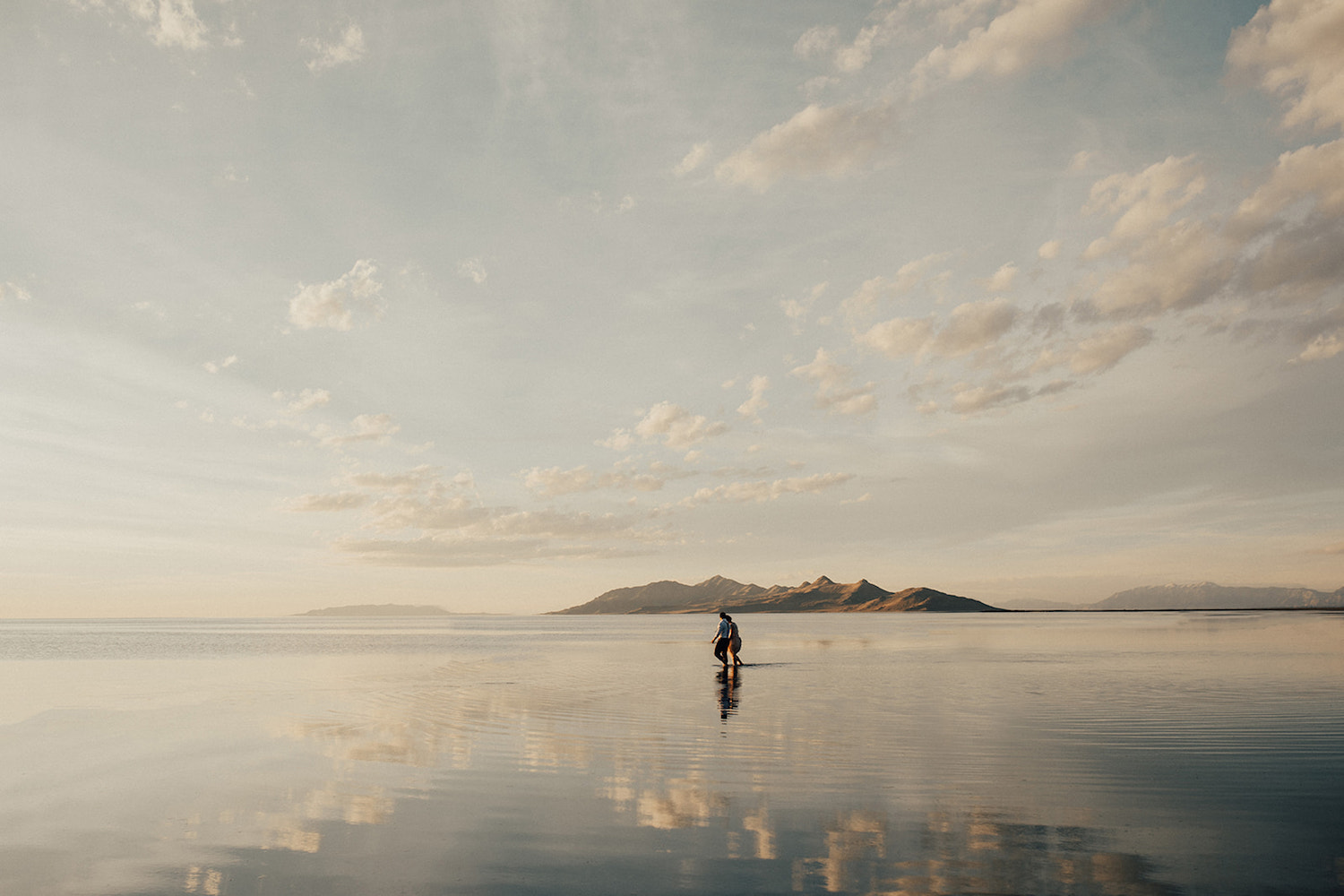 Image of a couple holding hands while walking across the Bonneville Salt Flats, photographed by Alexa Ann Photography.