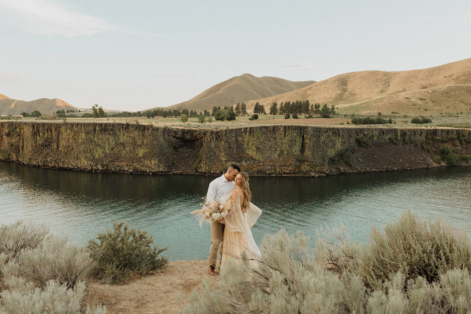 Couple share an intimate embrace overlooking a breathtaking view of the lake during their Idaho elopement, shot by Alexa Ann Photography