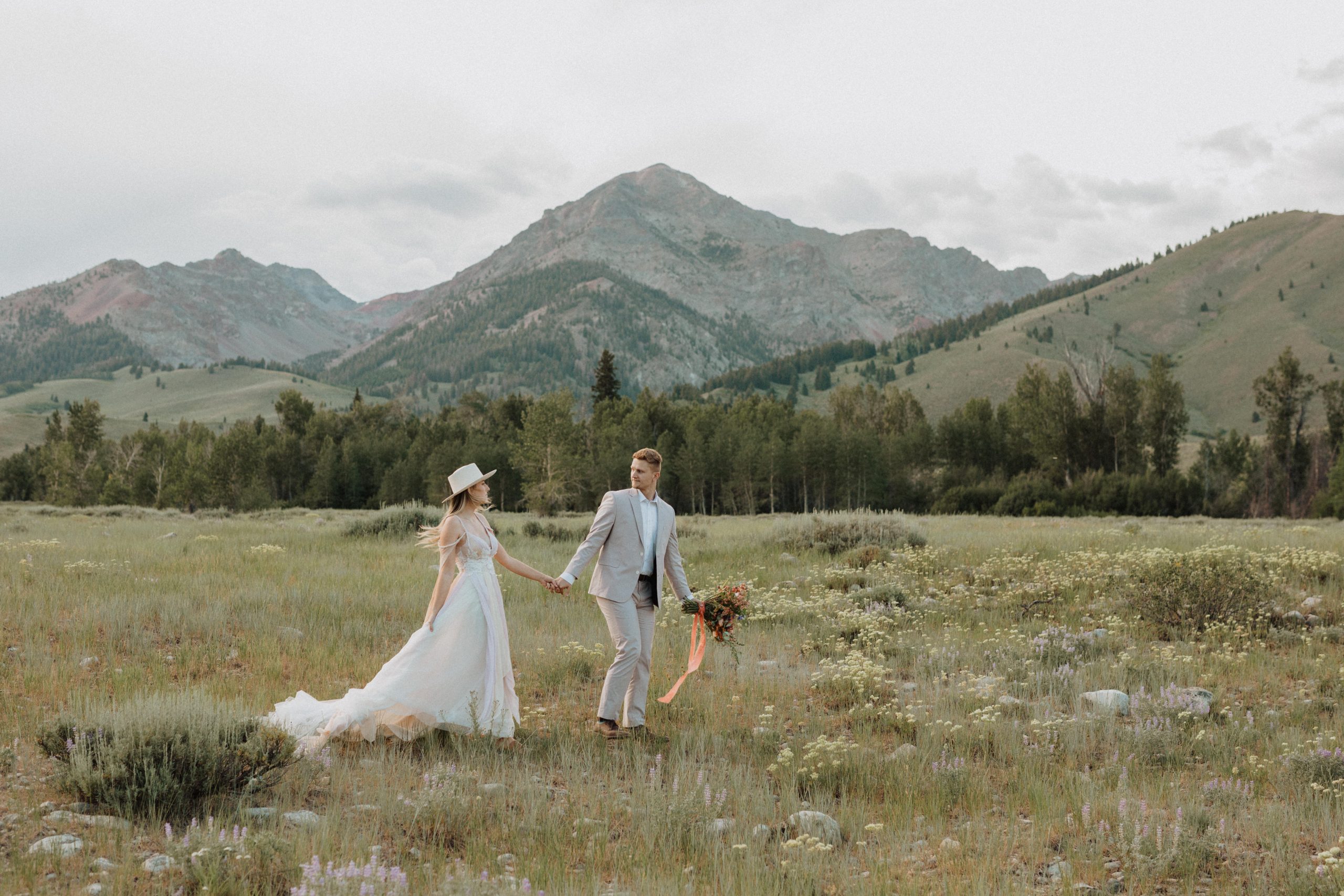 Bride and groom strolling through the grassland hand-in-hand at Sawtooth Wilderness, taken by Alexa Ann Photography