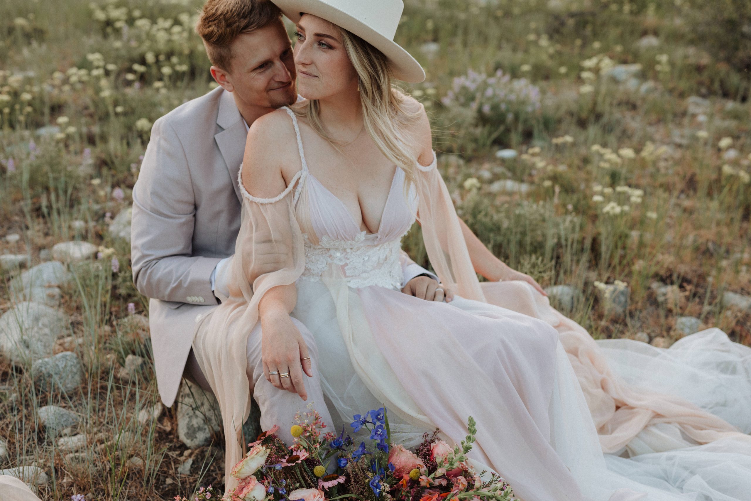 How to Elope in Stanley, Idaho: A Complete Guide. Couple sitting in the middle of the field and smiling during their elopement shoot with Alexa Ann in Idaho