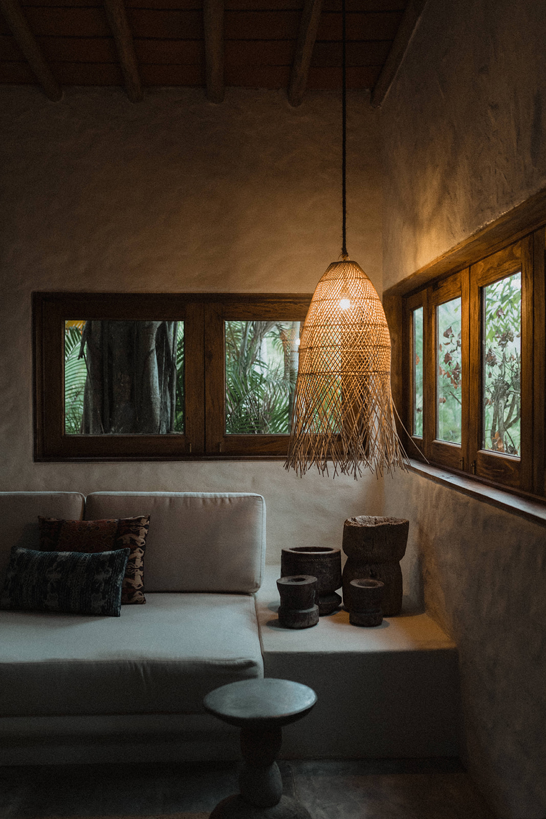 How to Elope in Mexico: The Ultimate Guide. Lounge corner at a venue in Mexico with a hanging lamp and bed, with windows.