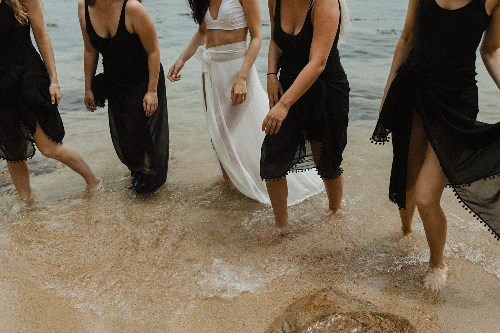 Close-up shot of bride with her bridesmaids walking on the water in Mexico during the elopement shoot with Alexa Ann
