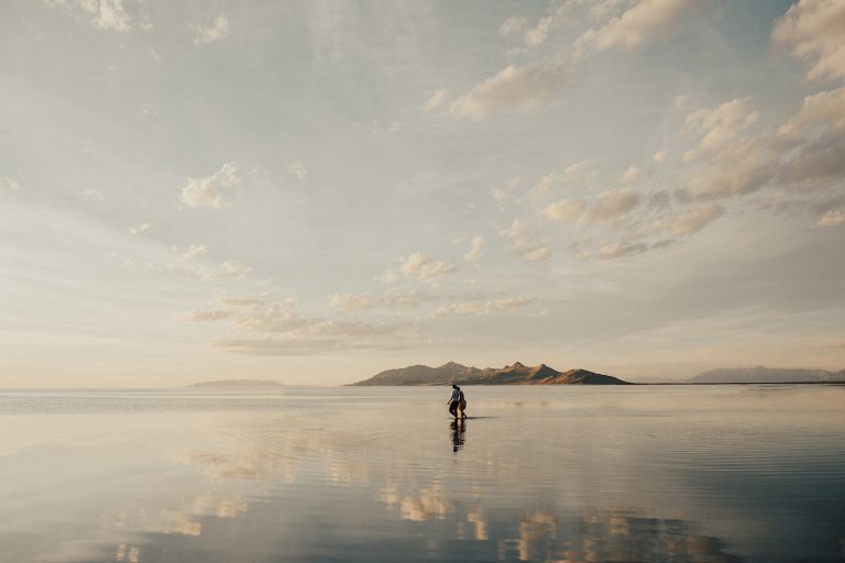 Image of a couple holding hands while walking across the Bonneville Salt Flats, photographed by Alexa Ann Photography.