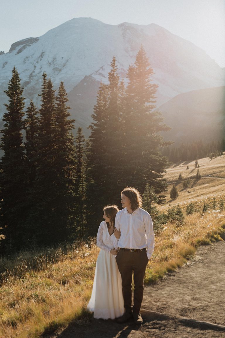 A couple stand side-by-side on a walking path at golden hour during their Washington state elopement