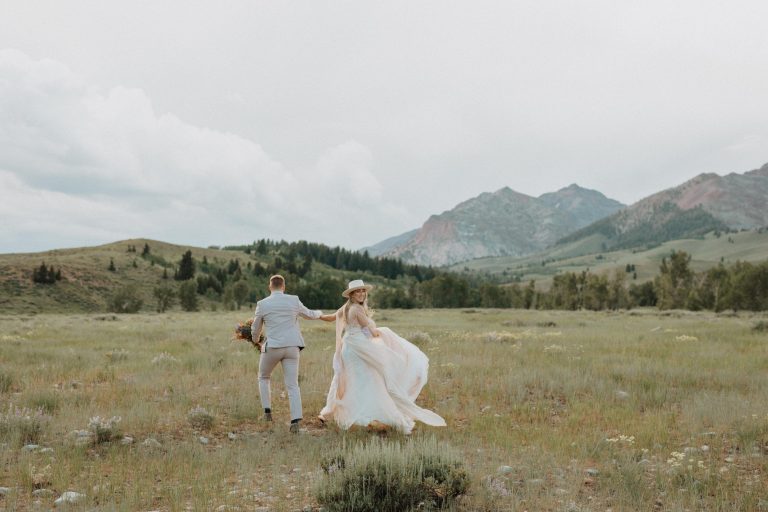 Bride and groom run around on the grassland during their elopement shoot in Idaho, taken by Alexa Ann Photography