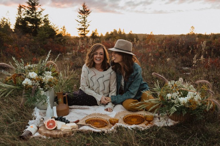Couple smile as they hold hands on the picnic mat set on the grass at Dolly Sods Wilderness