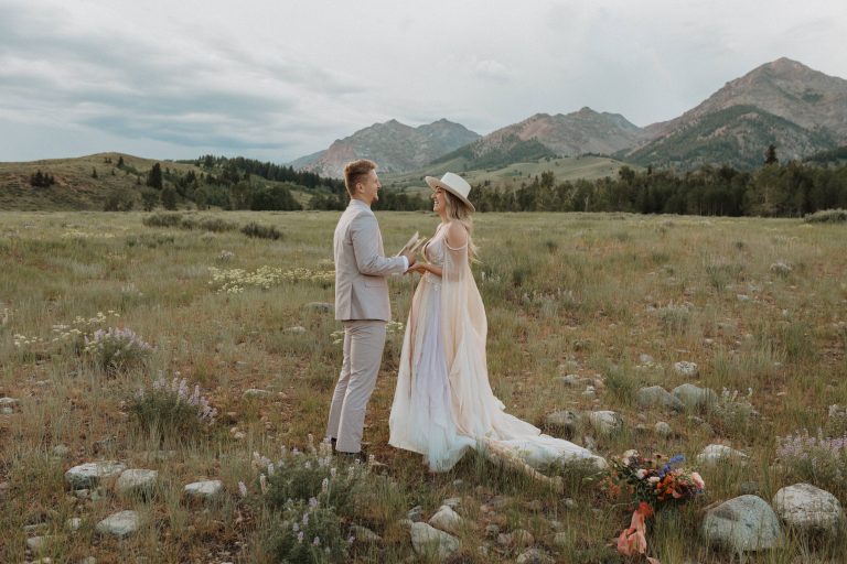 Couple hold hand and stand in front of each other in the middle of the fields at Sawtooth Mountain, Idaho