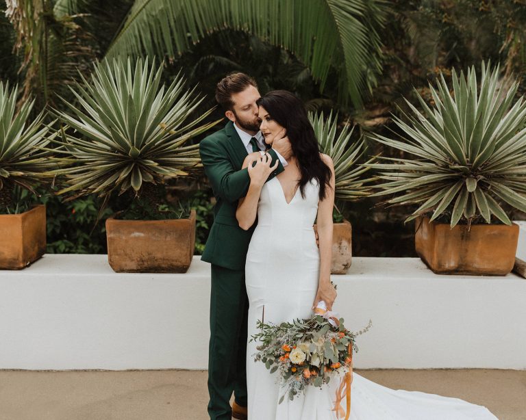 How to Elope In Mexico: Groom hugs bride from behind as he plants a kiss on her cheek while she smiles, captured by Alexa Ann Photography